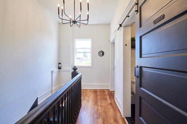 Love this hallway with black highlights like the bathroom barn door, staircase and lighting. Gorgeous!