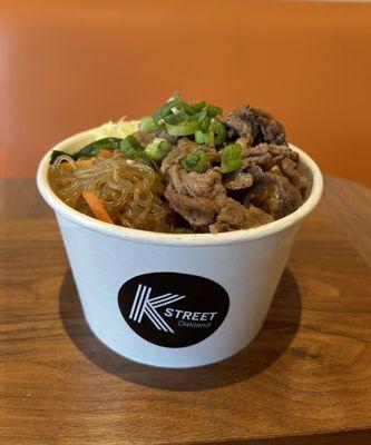 The cup comes with rice, vegetables, japchae, and one of three delicious protein sauces.