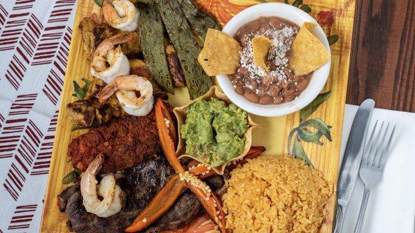 Parillada Ricoy, Chicken, Steak, Chorizo, and Shrimp accompanied by cactus, rice, beans, and a side of guacamole