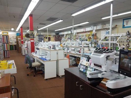 Brother embroidery machine front right. Sewing supplies in the background. Some of the Janome, Juki, Brother & Pfaff sewing machines.