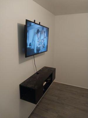 Mounted t v and cabinet on wall.