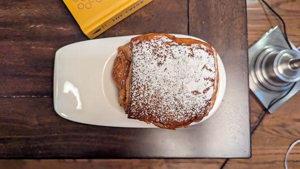 Flaky pain au chocolat heavily dusted with powdered sugar.