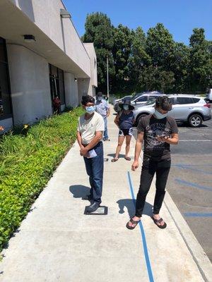 People in line in the sun to go inside the building.