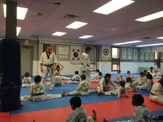 A regular after school class. The masters are making sure all the students do their stretches and moves correctly.