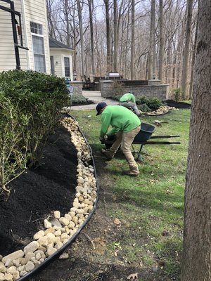 Landscape installation with river cobble around the flowers beds