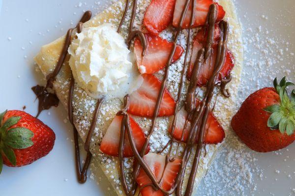 Strawberry Crepe with fresh strawberries, Nutella drizzle, powdered sugar and whipped cream. Also available gluten free.