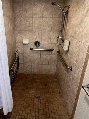 Accessible shower, room 133. Shower bench attached to the wall on left. Shower wand on right wall adjustable to several heights.