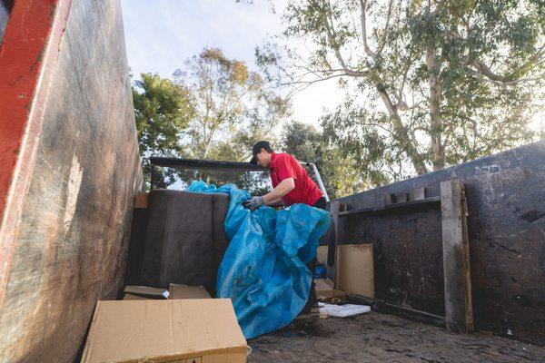 Setting up a furniture tarp over an old chair being moved.