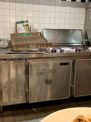 Dirty rack near the open refrigerator of meat.