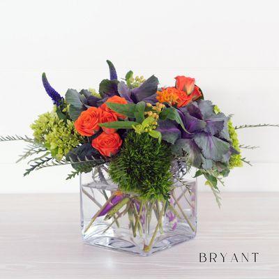 The Bryant, rich orange spray roses and purple kale set on a mound of hydrangea and trick.