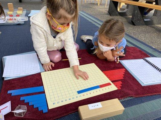 Collaborating on Math work using a Montessori material.