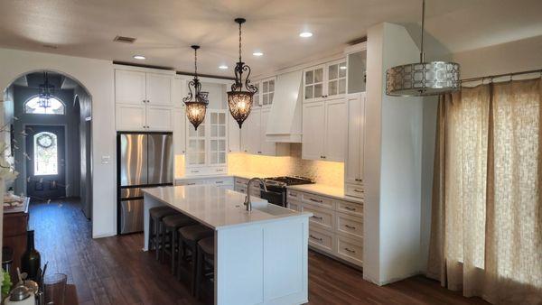 Beautiful twist on classic kitchen with custom cabinetry painted white, undercabinet lighting, island pendants