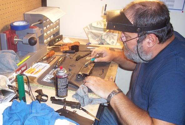 At the workbench cleaning a shotgun.