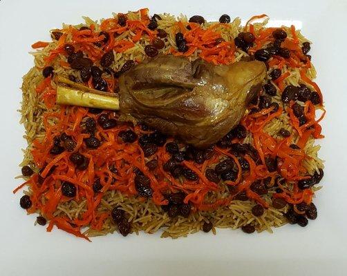 Quabuli Palow: rice seasoned with raisins and carrots with a lamb shank on top.