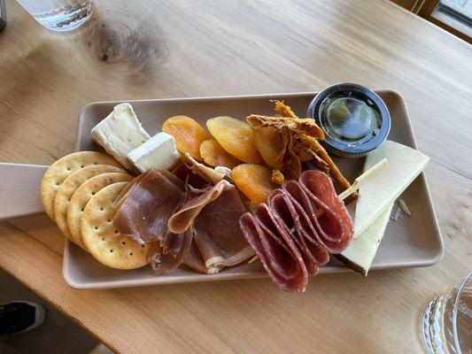 Our charcuterie board with brie, manchego, ham and salami, crackers, olives, dried mango and apricots.