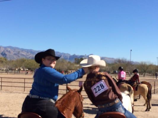 2 students of head to tail riding school helping one another before entering the show ring .