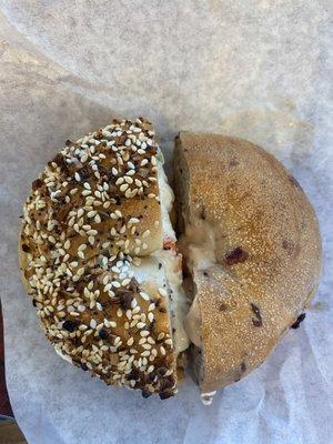 Half of an everything bagel with vegetable cream cheese, and half of a blueberry bagel with honey and walnut cream cheese.