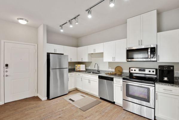 Kitchen and dining room with faux wood flooring, quartz countertops, and  stainless steel appliances at Lantower Edgewater.