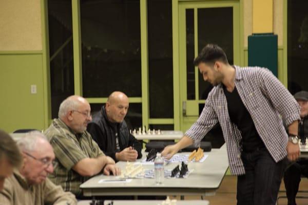 Grand Master Ioan Christian Chirila giving a simultaneous exhibition against players of the Kolty Chess Club.