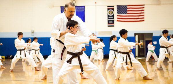 Sensei Dipasquale helping a brown belt student with his form in class.