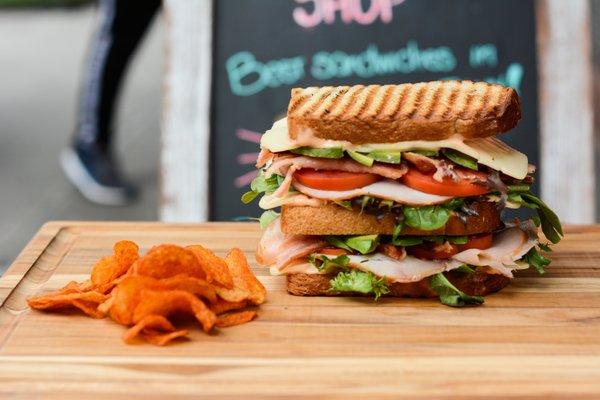 Turkey Club: Turkey Breast, Bacon, Swiss Cheese, Mesclun, Avocado, Tomato, and Russian Dressing on White Pullman Bread.