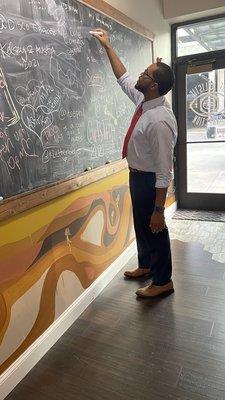 Husbae writing on the chalkboard looking like a whole professor