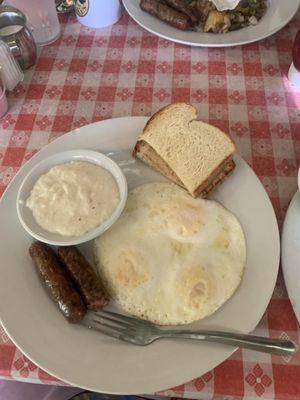 Three eggs, two sausage links, a bowl of grits, and a side of buttered toast.