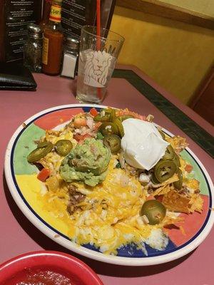 Nachos topped with shredded cheese, refried beans, ground beef, jalapeños, sour cream and pico de gallo.