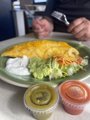 Smothered ground beef burrito with a side of sour cream, avocado and lettuce and are famous, red and green sauce