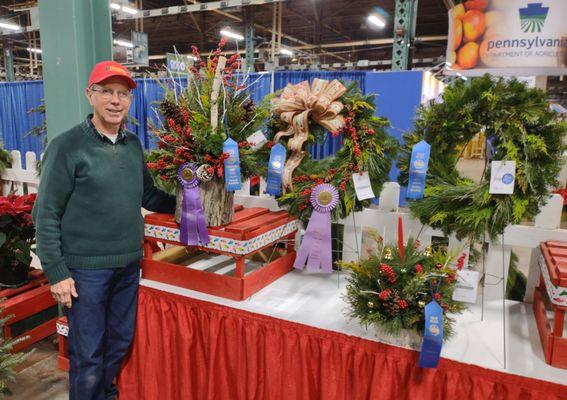 4 blue ribbons and a grand champion (porch pot) at 2024 PA Farm Show. Mixed green wreaths, porch pot, & centerpiece are featured for sale.