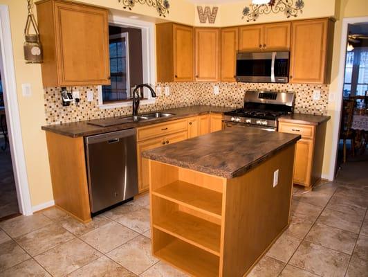 The optimizers within the cabinets of this refaced kitchen include shelf rollouts, a tip-out tray at the double sink and a tray divider.