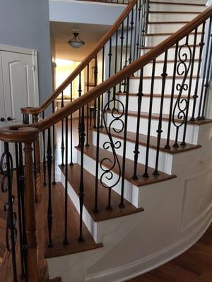 Stairs with iron balusters with matching stain on floors, handrails and stair treads