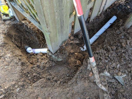 Whoever installed this fence put the post cement right through the elbow connecting these pipes.  Dug out, diverted around post, new pipes