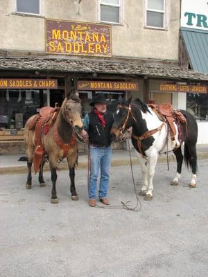 Les Kellem displaying saddles made in the shop.  The saddle on the right was made by his daughter.