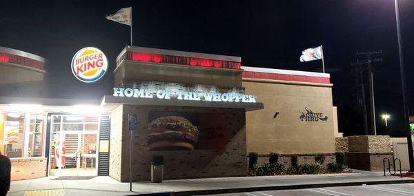 Burger King storefront at night. "Home of the Whopper," the sign reads, and the Burger King logo is featured too.