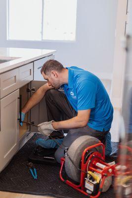 Technician is working on clearing a blockage in the kitchen sink drain