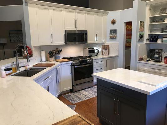 Microwave and stove centered on wall with equal size wall cabinets on each side.