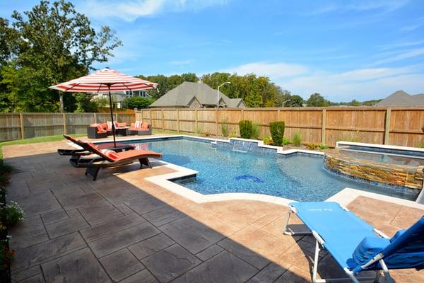 Geometric swimming pool with built-in ledges, spillover spa, and fountain