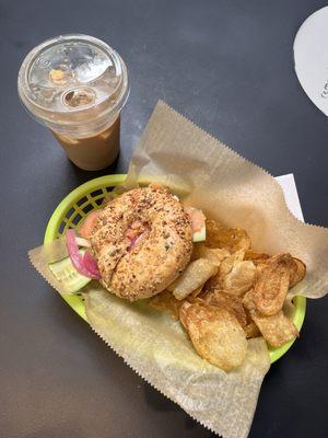 Lox bagel on an everything bagel (lox, pickled red onion, cucumber, capers, cream cheese) with a banana cold brew