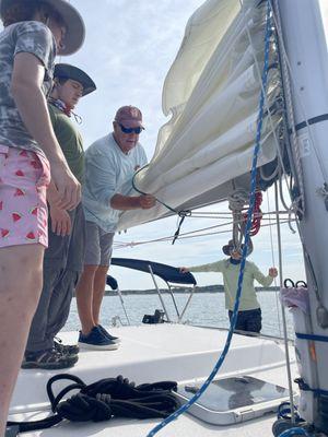 The boys helping the captain with the sail.