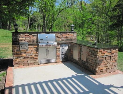 Gorgeous outdoor kitchen with granite countertop, outdoor sink, grill, built in lighting.