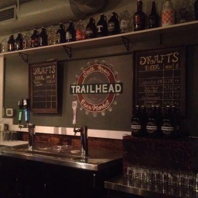 Behind the bar: 2 chalkboards with what's on draft, awesome artwork of the Trailhead logo, and so many growlers!!