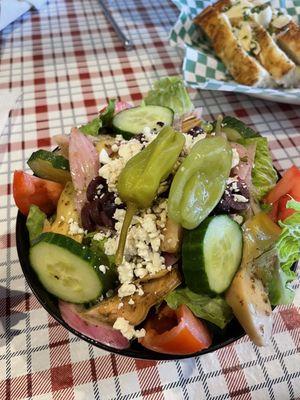 Small Greek salad with a side of focaccia bread.