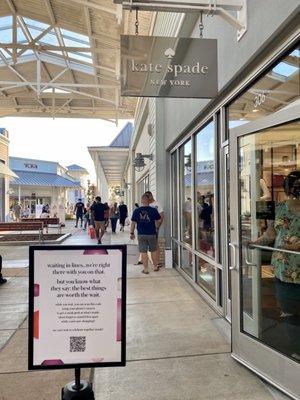 The line outside to limit the number of customers, and sign about social distancing & mask moutside the Kate Spade store.