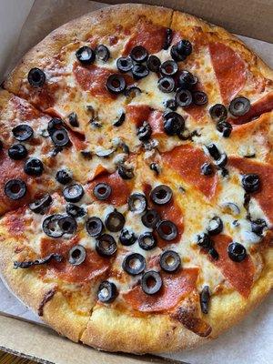 Pepperoni pizza with black olives in to-go box.