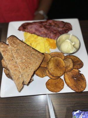 Turkey bacon, potatoes, wheat toast , and scrambled eggs with cheese .