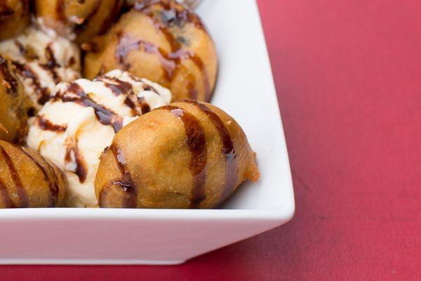 Deep fried oreos topped with chocolate drizzle and a side of vanilla ice cream