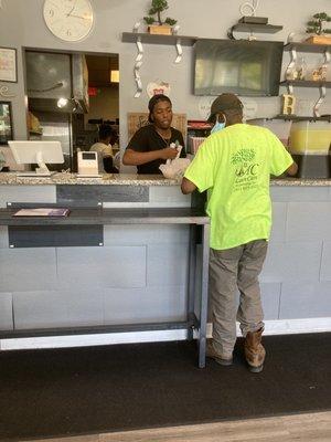 Kind male cashier wraps up customer's take-out order and offers condiments.