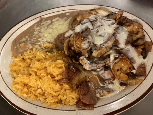 Crema Supreme- chicken, shrimp, mushrooms, onions, bacon, and ham topped with cheese sauce served with rice and beans.