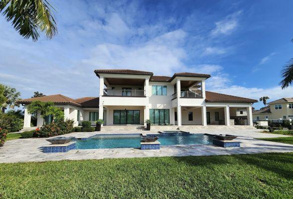 A front view of a luxury house with a swimming pool in the foreground, showcasing the property's amenities and architectural ...